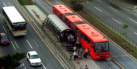 A bus in Curitiba stops to pick up and drop off passengers. Notice the dedicated lane and the station that allows for level boarding at all doors.
