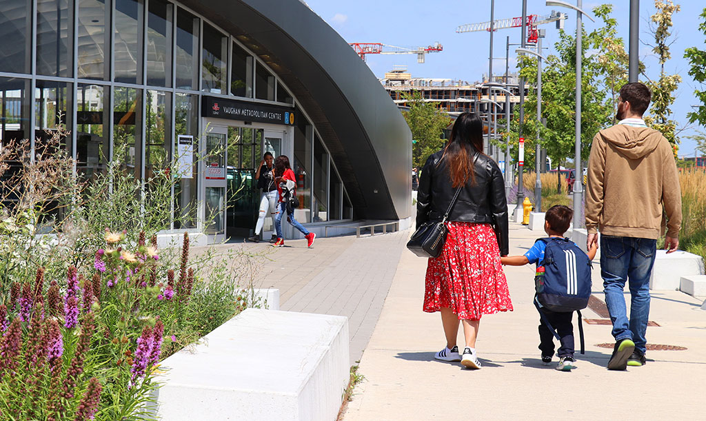 A family of three walks towards Vaughan Metropolitan Subway station, one of the stations built as part of the Toronto-York Spadina Subway Extension.