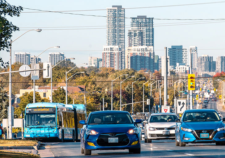 A bus and cars drive across a busy highway 7 east.