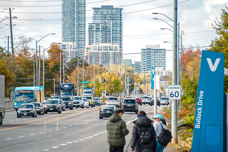 A bus and cars drive across a busy highway 7 east.