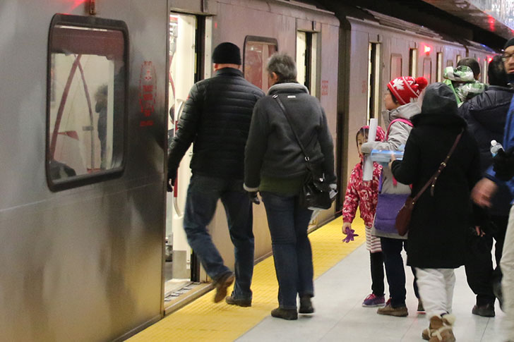 A group of people board a TTC subway.